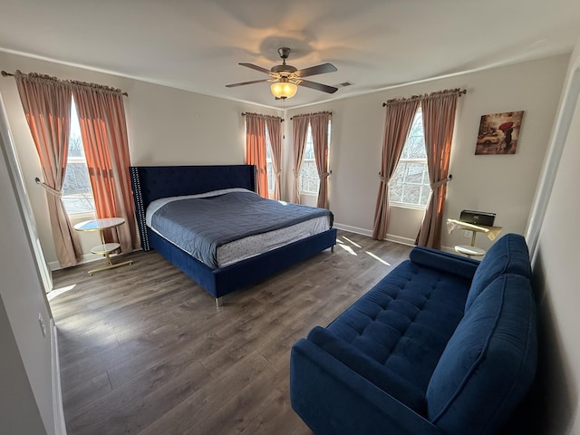 bedroom with a ceiling fan, baseboards, visible vents, and wood finished floors