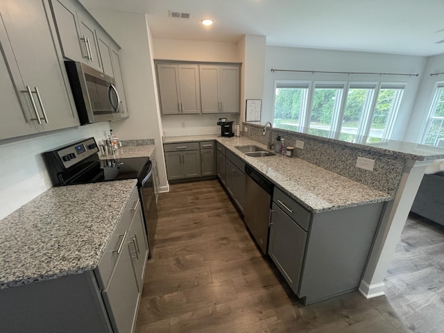 kitchen featuring stainless steel appliances, gray cabinets, visible vents, a sink, and a peninsula