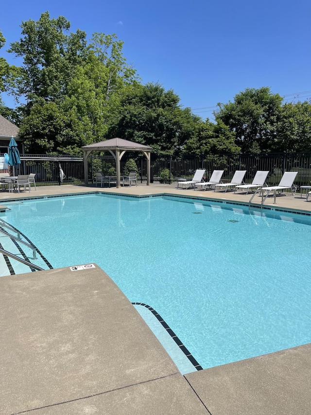 community pool with a patio area and fence