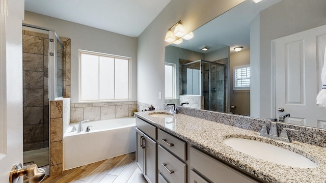 bathroom with a stall shower, a garden tub, a sink, and double vanity