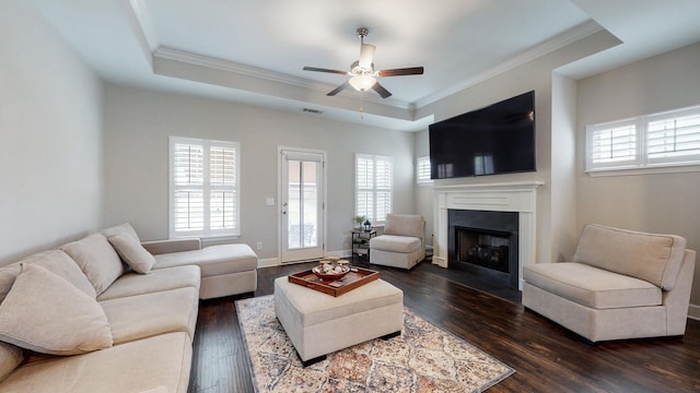 living room with a fireplace with flush hearth, dark wood-style flooring, a raised ceiling, and a wealth of natural light