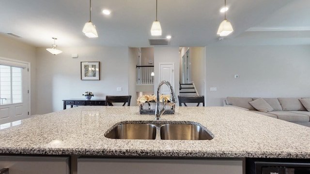 kitchen with light stone countertops, visible vents, open floor plan, and a sink