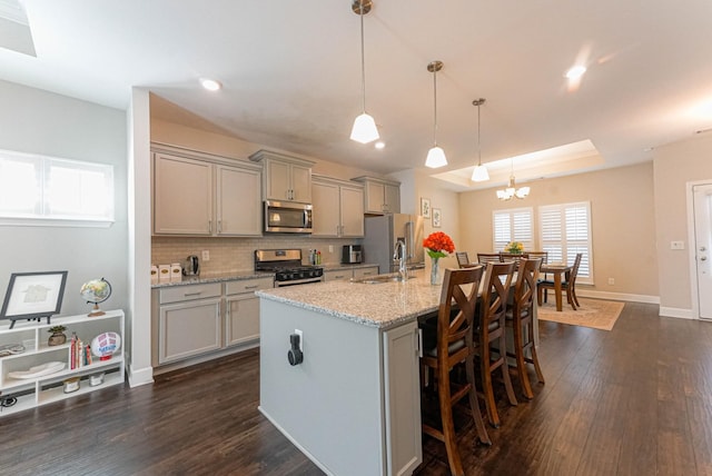 kitchen featuring a sink, stainless steel appliances, gray cabinets, and a kitchen island with sink