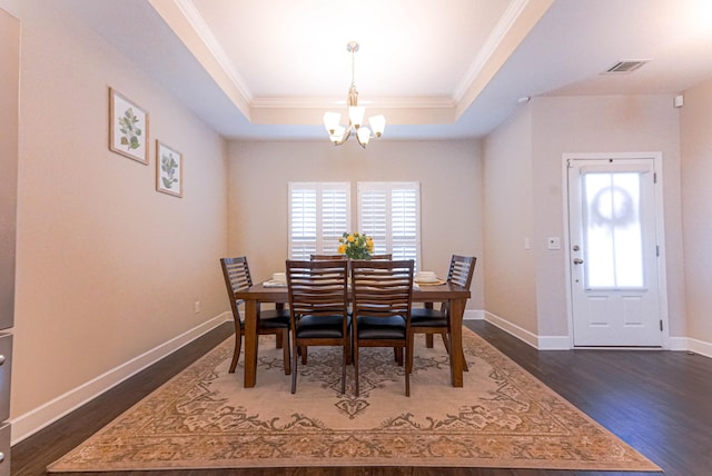 dining area featuring dark wood-type flooring, visible vents, baseboards, a raised ceiling, and an inviting chandelier