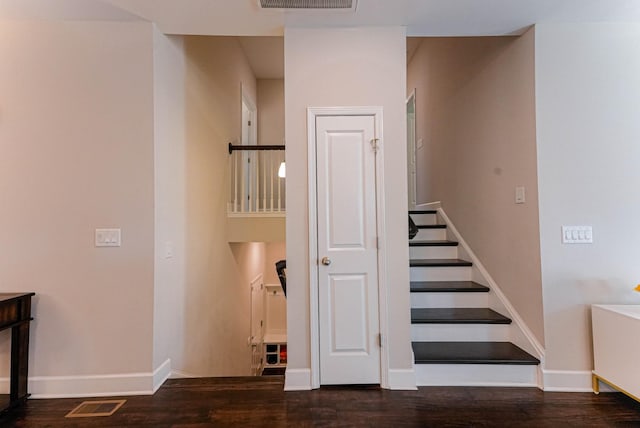 stairway with baseboards, visible vents, and wood finished floors