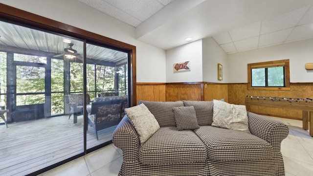 living area featuring a wainscoted wall, ceiling fan, and wooden walls