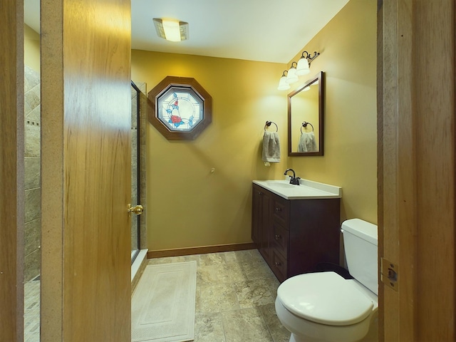 bathroom with vanity, a shower stall, toilet, and baseboards