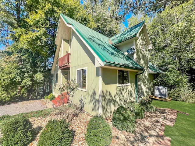 view of side of property with metal roof, a lawn, and a balcony