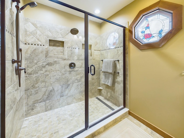 bathroom with a shower stall, baseboards, and tile patterned floors