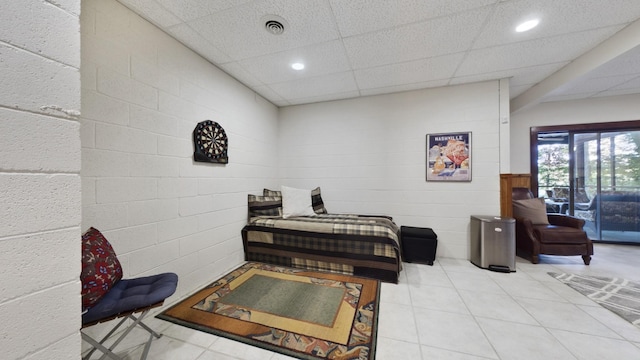 interior space featuring a drop ceiling, concrete block wall, visible vents, and recessed lighting