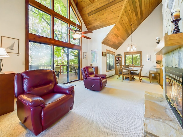 interior space with a wealth of natural light, wood ceiling, a glass covered fireplace, and ceiling fan with notable chandelier