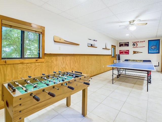 game room featuring a ceiling fan, wainscoting, a paneled ceiling, and wooden walls