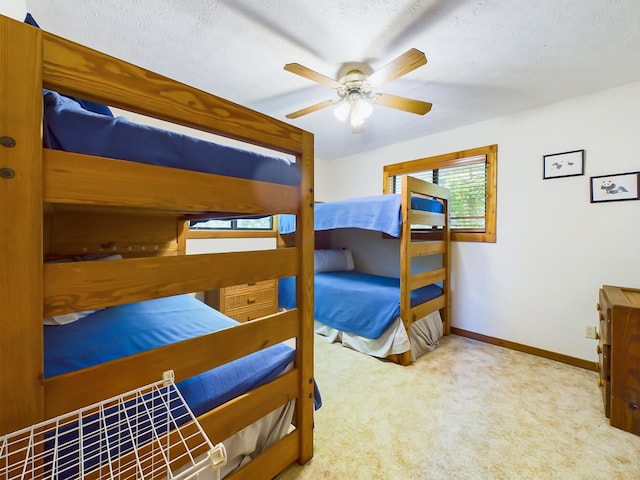 carpeted bedroom with a ceiling fan, a textured ceiling, and baseboards