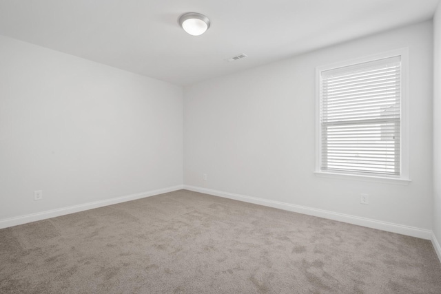 spare room featuring carpet, visible vents, and baseboards