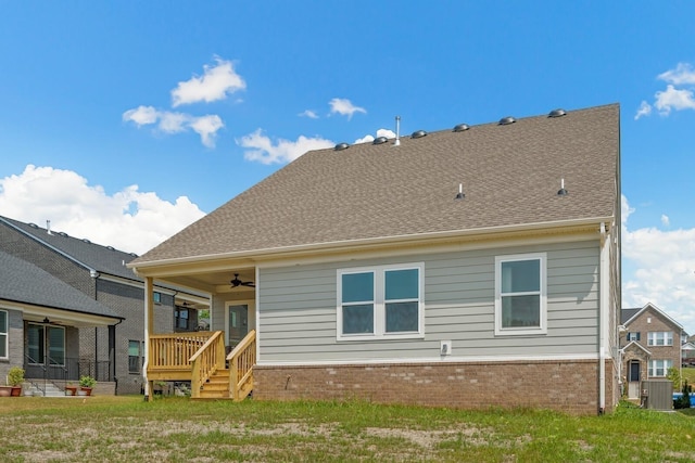 back of house featuring a yard, a shingled roof, a ceiling fan, and brick siding