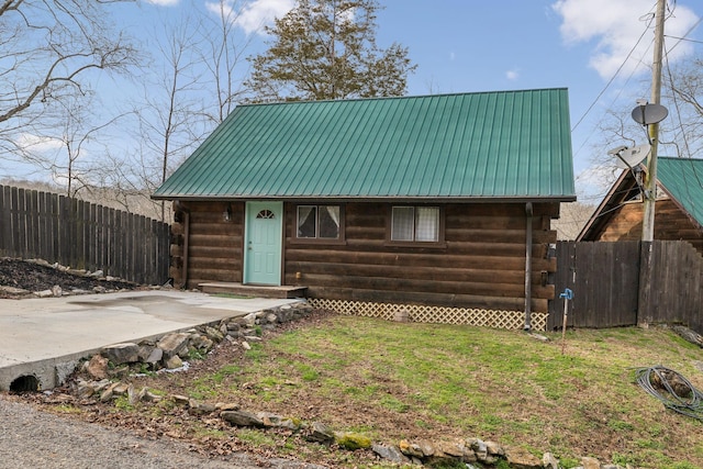 log home featuring metal roof, log exterior, a front lawn, and fence