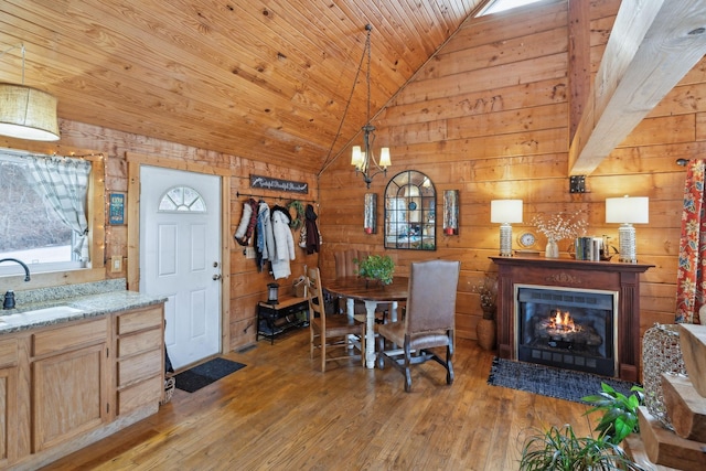 dining room with vaulted ceiling, wood walls, wood ceiling, and light wood-style floors