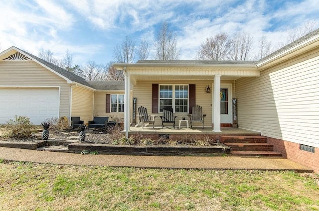 view of exterior entry featuring a garage, covered porch, and crawl space