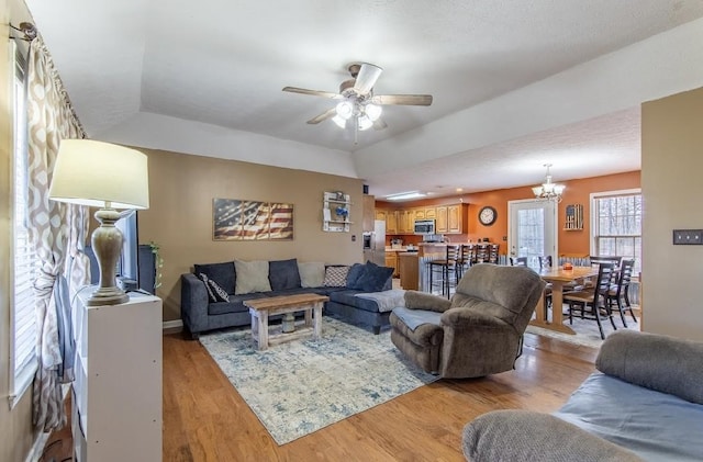 living room featuring light wood-style flooring and ceiling fan with notable chandelier