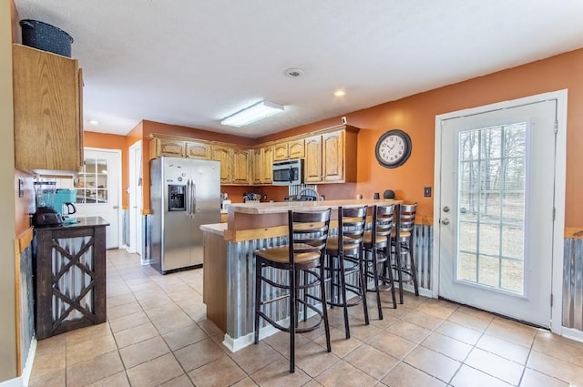 kitchen with stainless steel appliances, a healthy amount of sunlight, a peninsula, and a kitchen breakfast bar