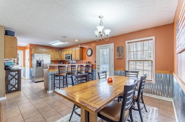 dining room featuring a wainscoted wall, a textured ceiling, and light tile patterned floors