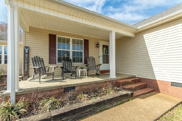 view of exterior entry with covered porch, a shingled roof, and crawl space