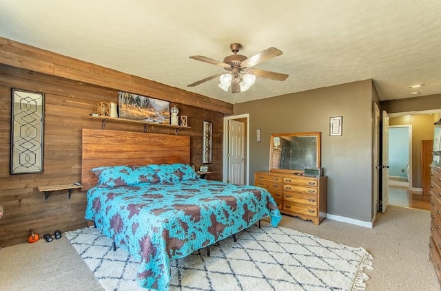 bedroom featuring ceiling fan, wooden walls, baseboards, and carpet flooring