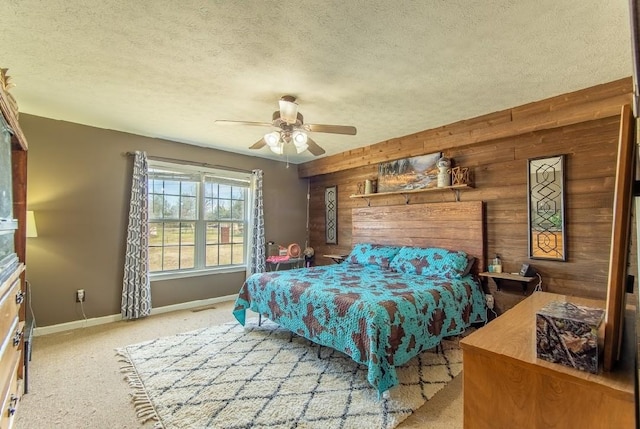 carpeted bedroom featuring wooden walls, visible vents, baseboards, a ceiling fan, and a textured ceiling