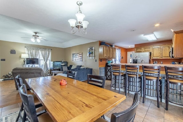 dining space with light tile patterned floors and ceiling fan with notable chandelier