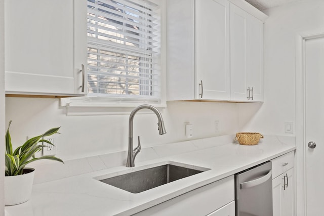 kitchen featuring dishwasher, a sink, white cabinetry, and light stone countertops