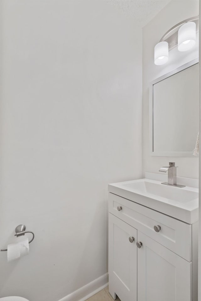 bathroom featuring baseboards, vanity, and a textured ceiling