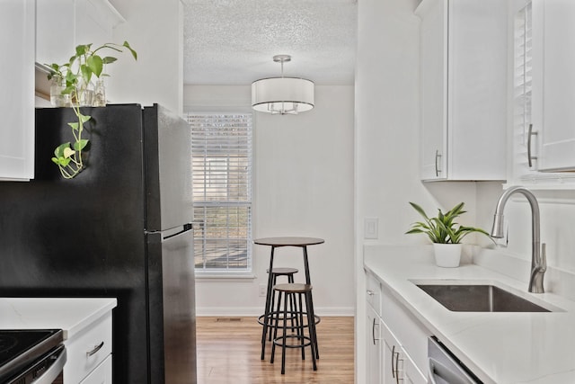 kitchen featuring a textured ceiling, light countertops, a sink, and freestanding refrigerator