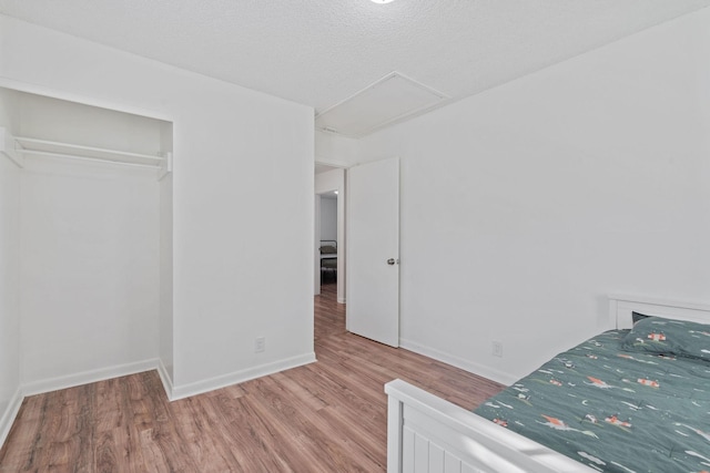 unfurnished bedroom with baseboards, a textured ceiling, and light wood finished floors