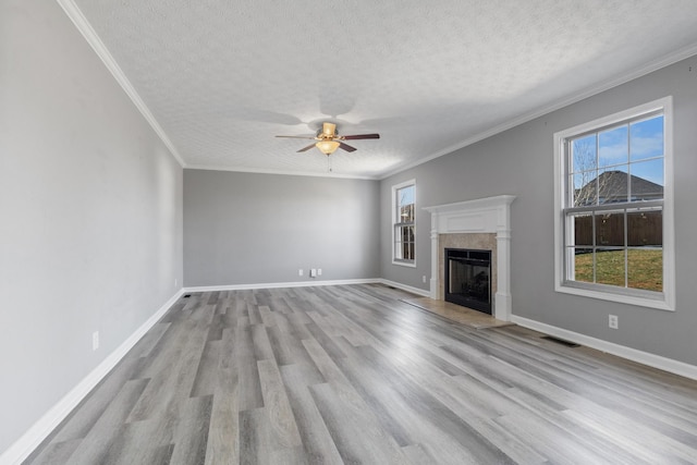 unfurnished living room featuring a fireplace with raised hearth, wood finished floors, visible vents, and baseboards