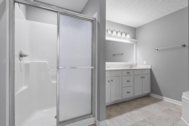 bathroom featuring a textured ceiling, a sink, baseboards, a shower stall, and double vanity