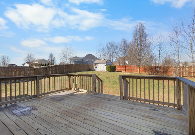 wooden deck with an outbuilding, a fenced backyard, a yard, and a storage unit