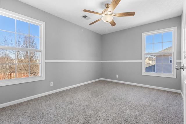 carpeted empty room with a ceiling fan, plenty of natural light, visible vents, and baseboards