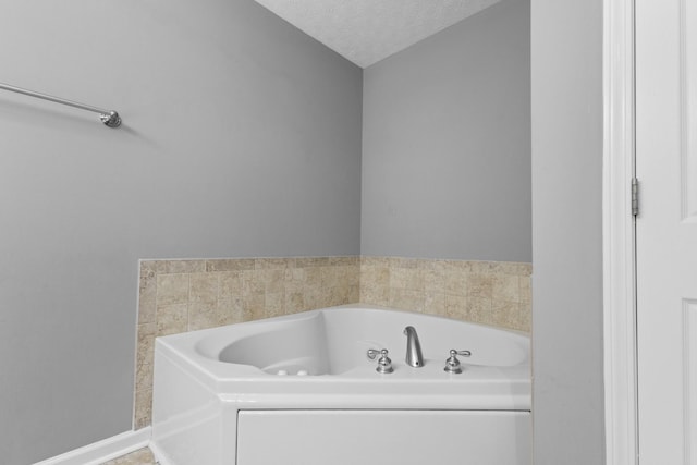 bathroom featuring a garden tub, a textured ceiling, and baseboards