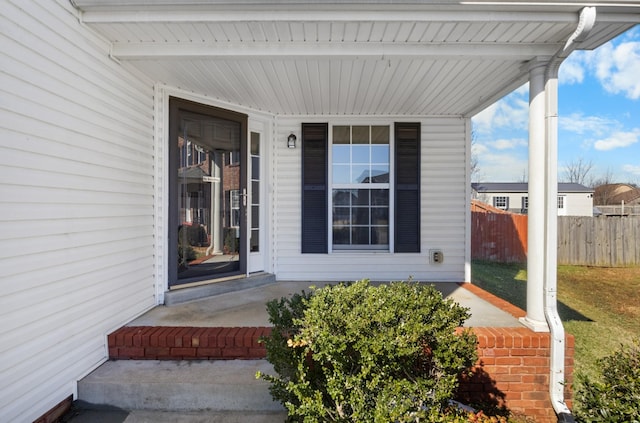 entrance to property with a porch and fence