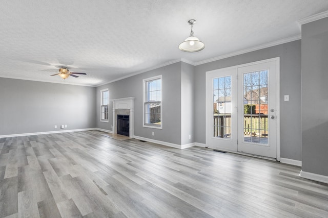 unfurnished living room with a textured ceiling, ornamental molding, a fireplace, and wood finished floors