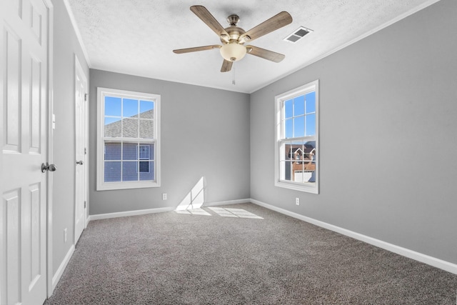 carpeted spare room with baseboards, visible vents, and a textured ceiling