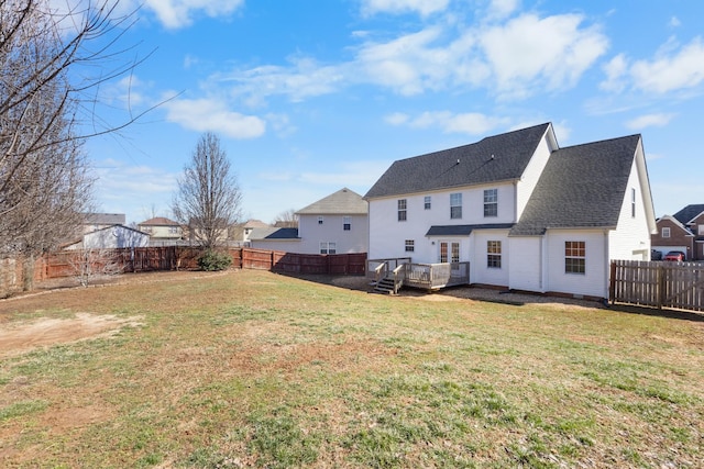 rear view of property featuring a fenced backyard, roof with shingles, a wooden deck, and a yard