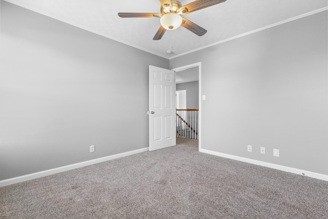 carpeted empty room featuring ceiling fan, baseboards, and ornamental molding