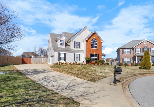 view of front of house with driveway, an attached garage, fence, a front lawn, and brick siding