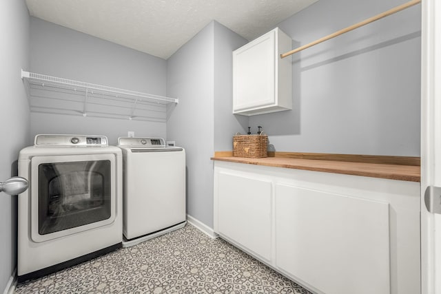 laundry area with a textured ceiling, baseboards, independent washer and dryer, cabinet space, and light floors