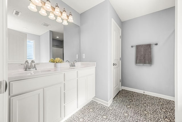 bathroom with double vanity, baseboards, visible vents, and a sink