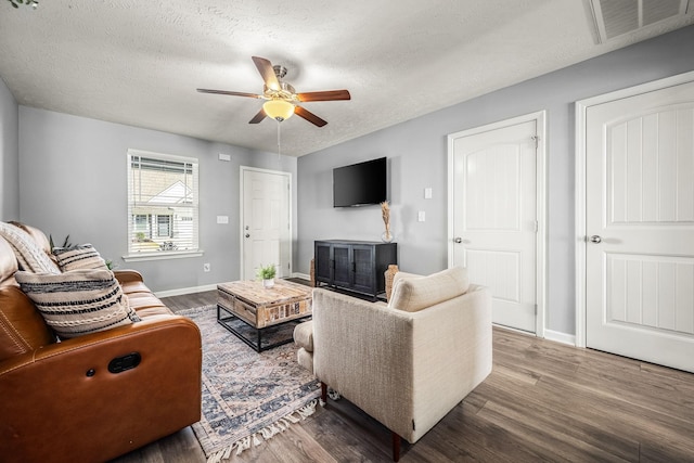 living area featuring a ceiling fan, a textured ceiling, visible vents, and wood finished floors