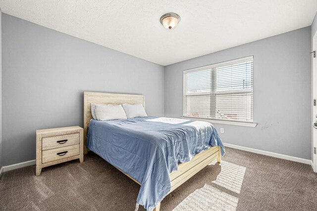 bedroom with dark carpet and baseboards