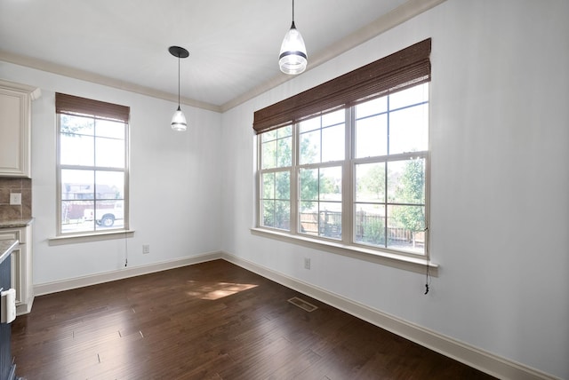 unfurnished dining area with plenty of natural light, dark wood finished floors, visible vents, and baseboards