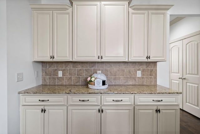 kitchen with light stone counters, white cabinets, dark wood-type flooring, and backsplash